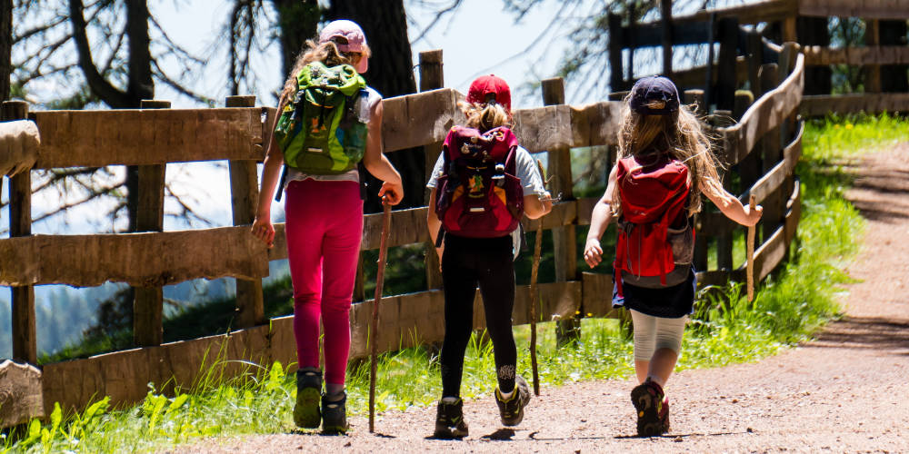 Un grupo de niñas hace senderismo por un camino soleado